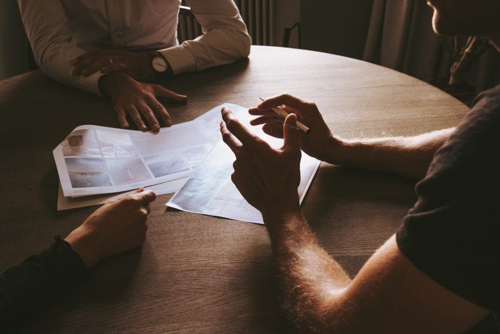 multiple people sitting around table discussing business document