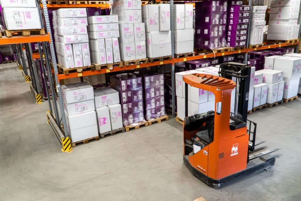 fork lift truck in warehouse aisle filled with pallets