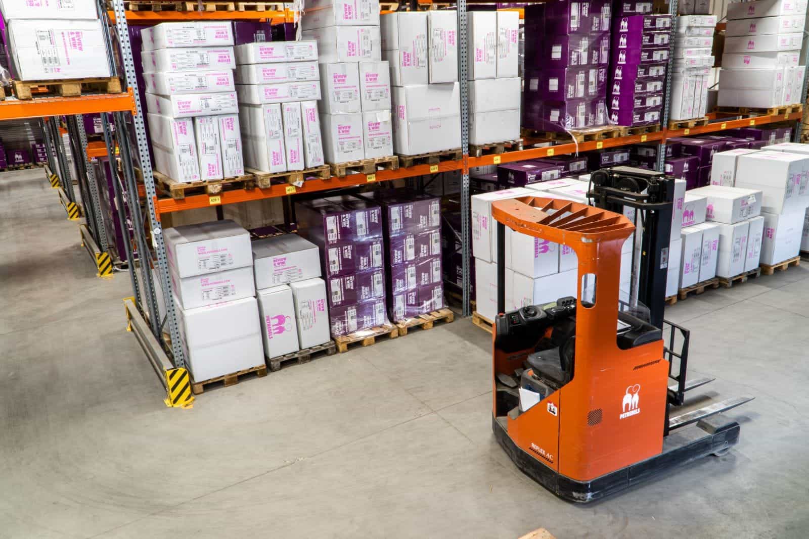 fork lift truck in warehouse aisle filled with pallets